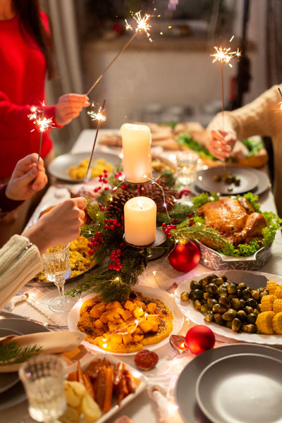 People celebrating a festive meal with sparklers and a roasted turkey on a table.