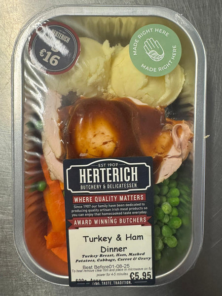 Herterich Turkey & Ham Dinner ready meal with turkey, ham, mashed potatoes, carrots, peas, and gravy in a clear plastic container.