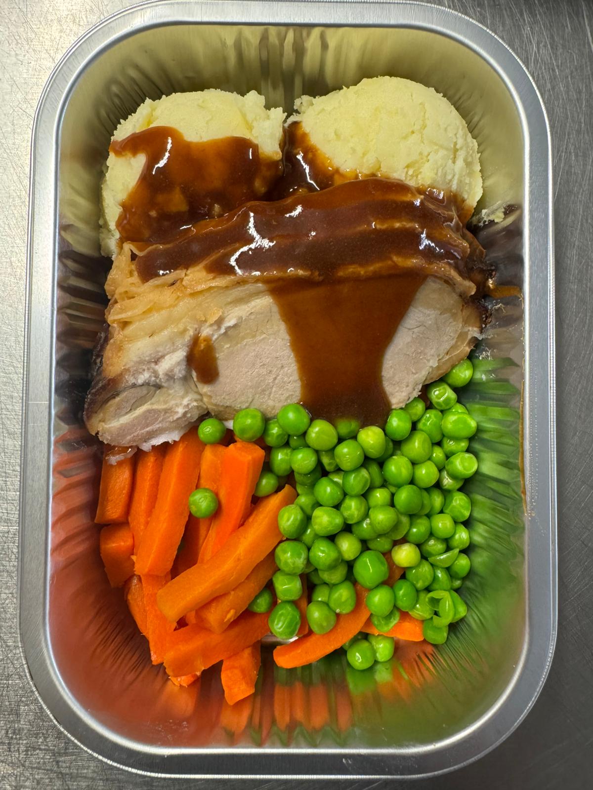 Herterich Roast Pork Dinner ready meal with roast pork, mashed potatoes, gravy, carrots, and peas in an aluminum tray.