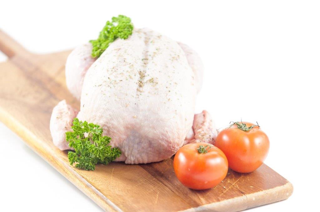 a Large Free Range Chicken on a wooden platter with parsley and tomatoes